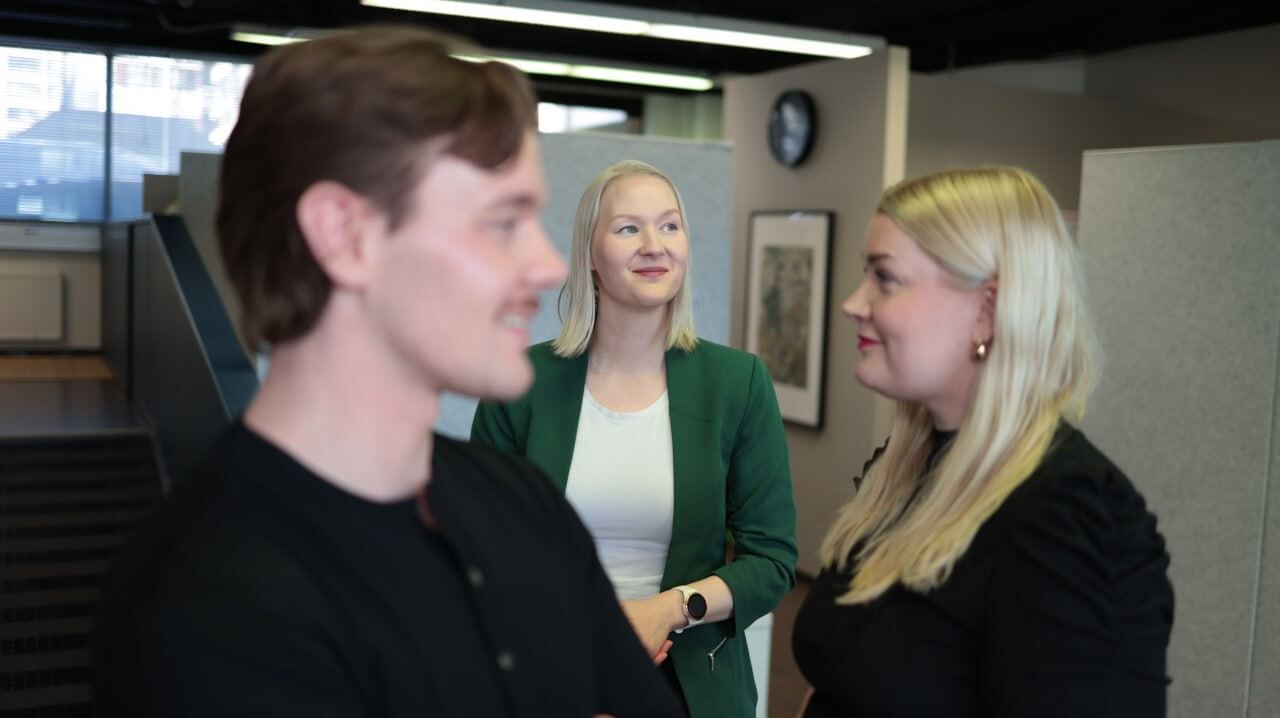 Kolme WorkPowerin toimihenkilöä toimistolla. Keskimmäisellä pohtiva ilme kasvoillaan.