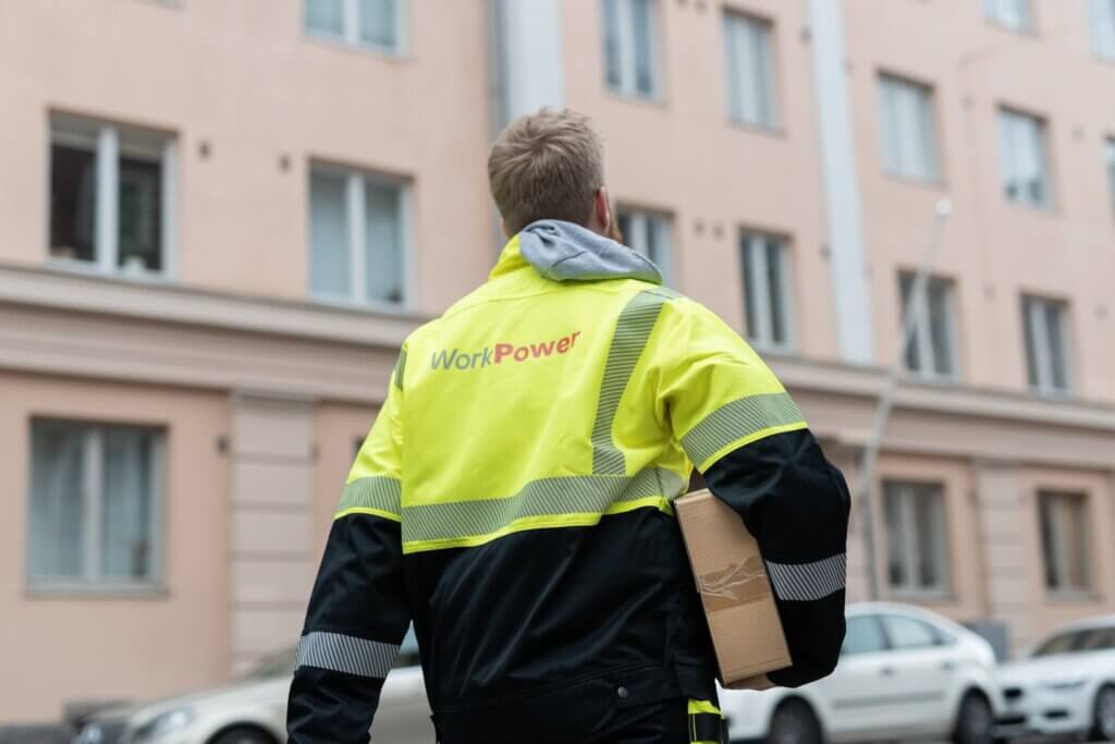 Työntekijä kuljettaa pakettia.