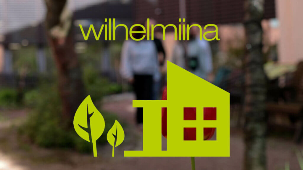 Kuvassa Wilhelmiinan logo ja taustalla henkilöitä pihalla.